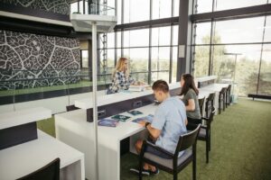 Franquia educacional com sala de estudos moderna onde alunos e orientador consultam materiais didáticos em mesas com vista panorâmica