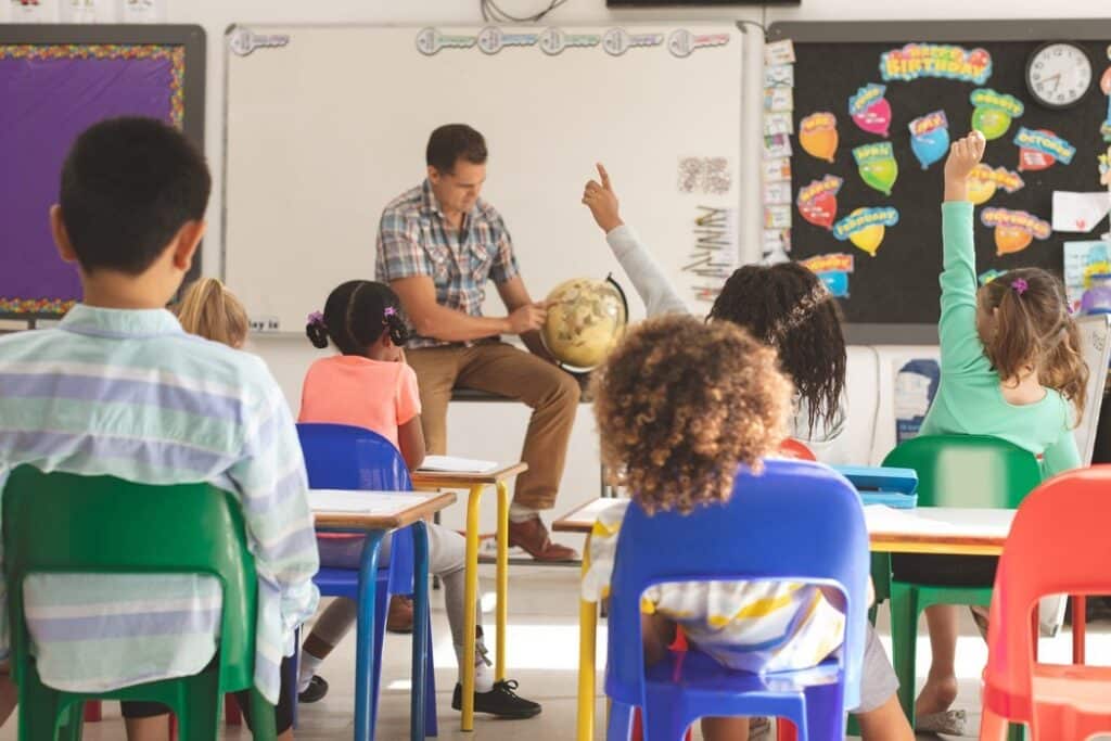 Professor com globo terrestre engajando alunos em sala de aula, refletindo a qualidade pedagógica que deve ser avaliada no COF de franquia