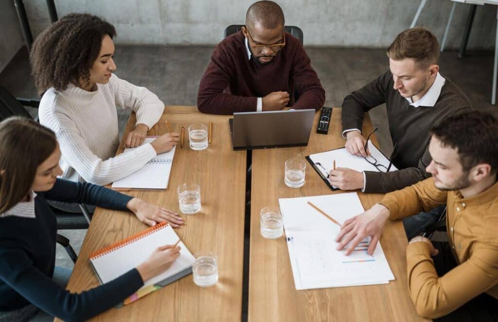 Equipe reunida analisando planejamento e dados em mesa de trabalho, representando o processo estratégico de como abrir uma escola particular.