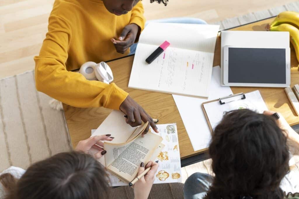 Alunos estudando em sala de aula de franquia de escola durante atividade em grupo com livros e materiais, ilustrando artigo sobre quanto custa uma franquia de escola