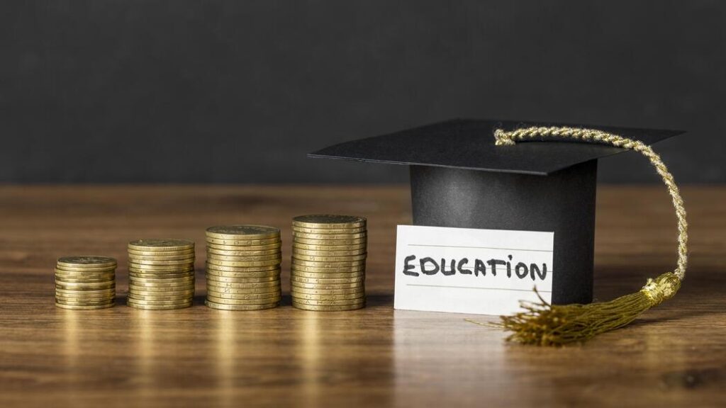 Pilhas de moedas ao lado de capelo de formatura, com placa onde se lê "Education", ilustrando sobre artigo franquia de escola vale a pena