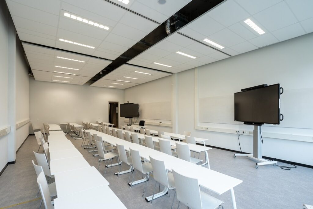 sala de aula moderna com mesas, cadeiras e lousas digitais, refletindo a infraestrutura esperada em uma unidade franqueada,  ilustrando artigo sobre franquia de escola vale a pena 