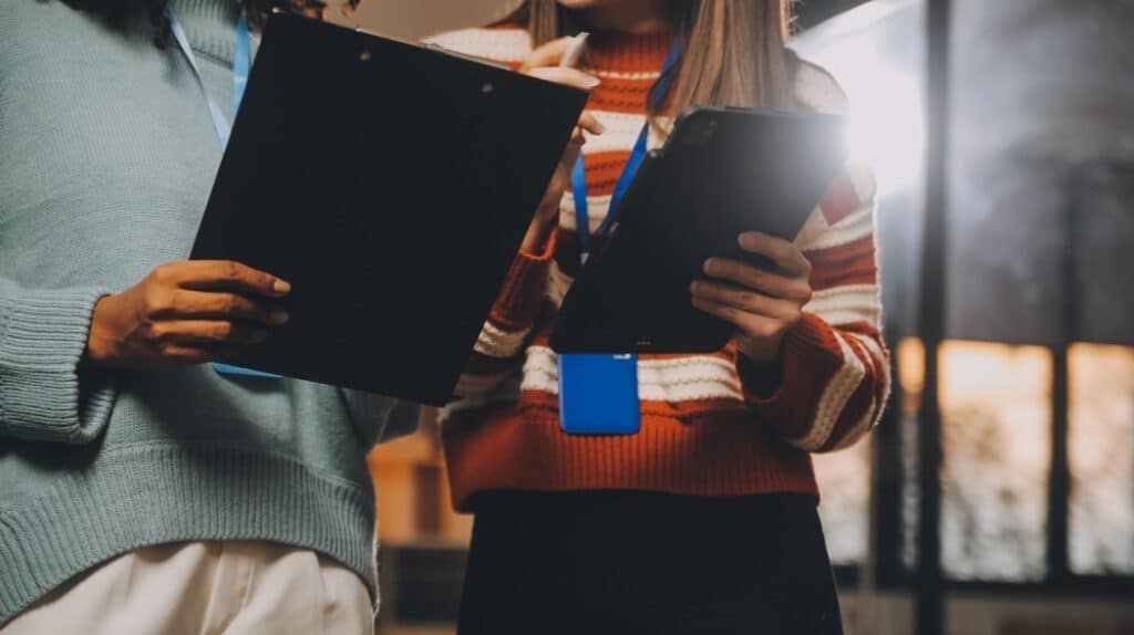 Duas profissionais analisando dados em prancheta e tablet, representando o mercado de franquias de educação como setor resiliente para investir.